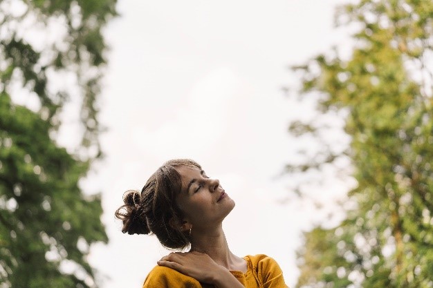 Person outdoors with eyes closed and face angled skyward