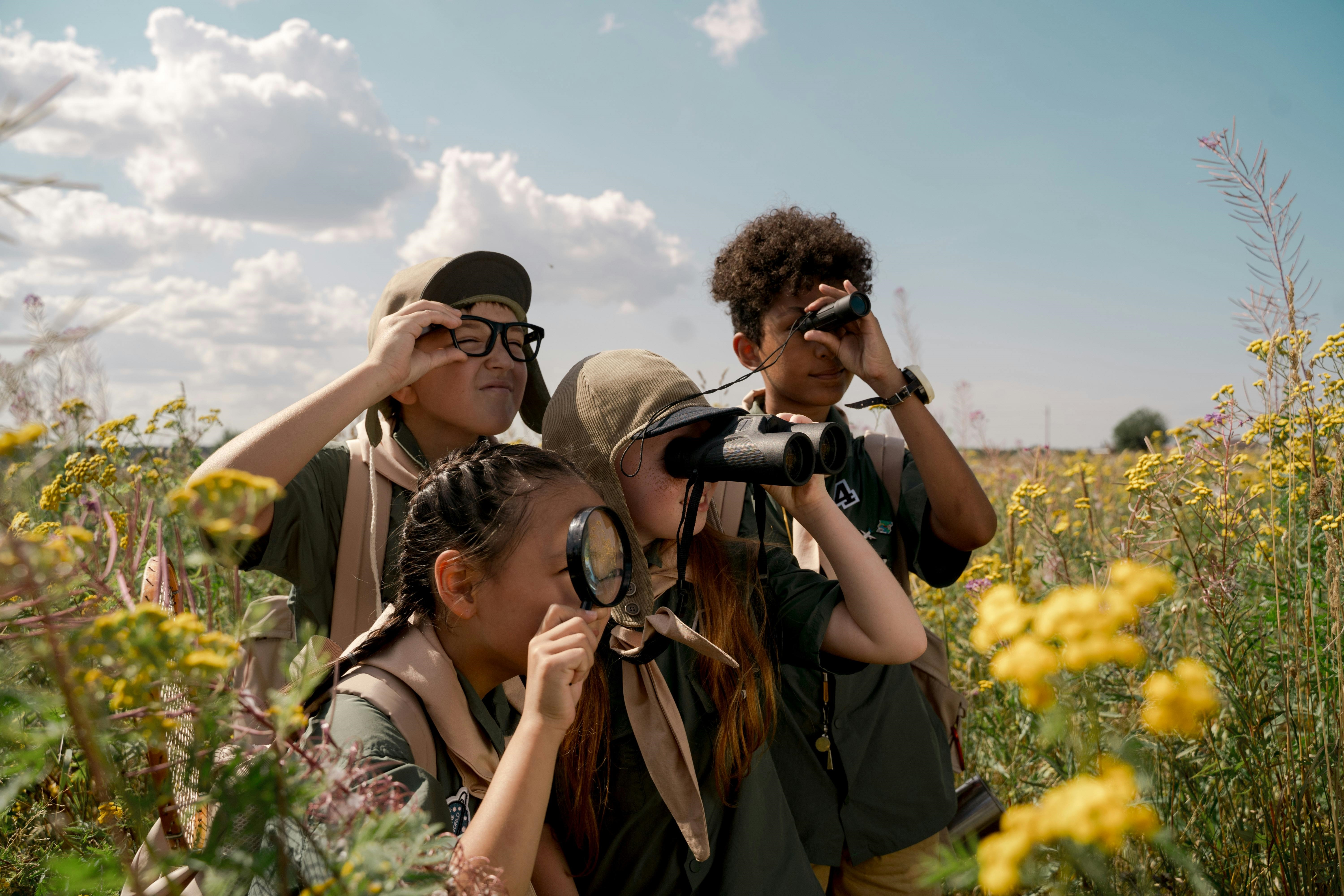 Four children with binoculas in field