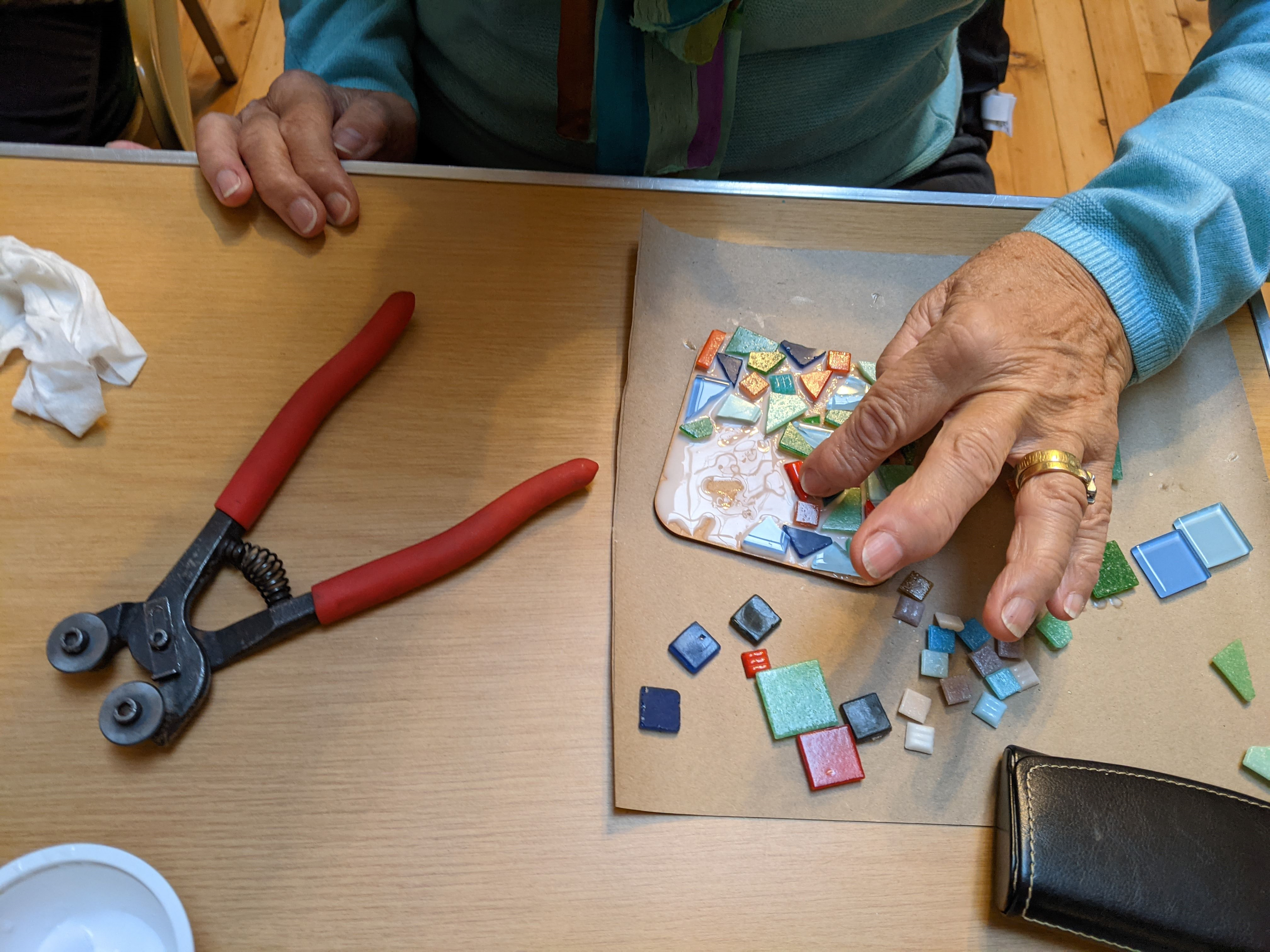 Hands arranging mosaic tiles with tools