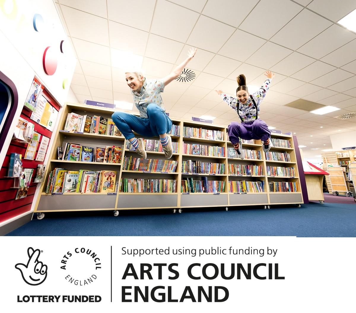 Two people jumping in the air in front of library shelves