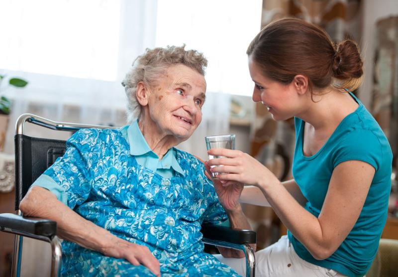 Carer handing a glass to woman