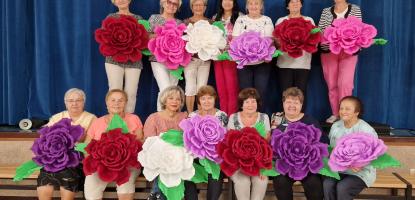 a group of ladies holding large paper flowers