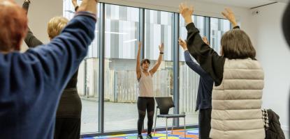 A group doing Tai Chi with their arms lifted